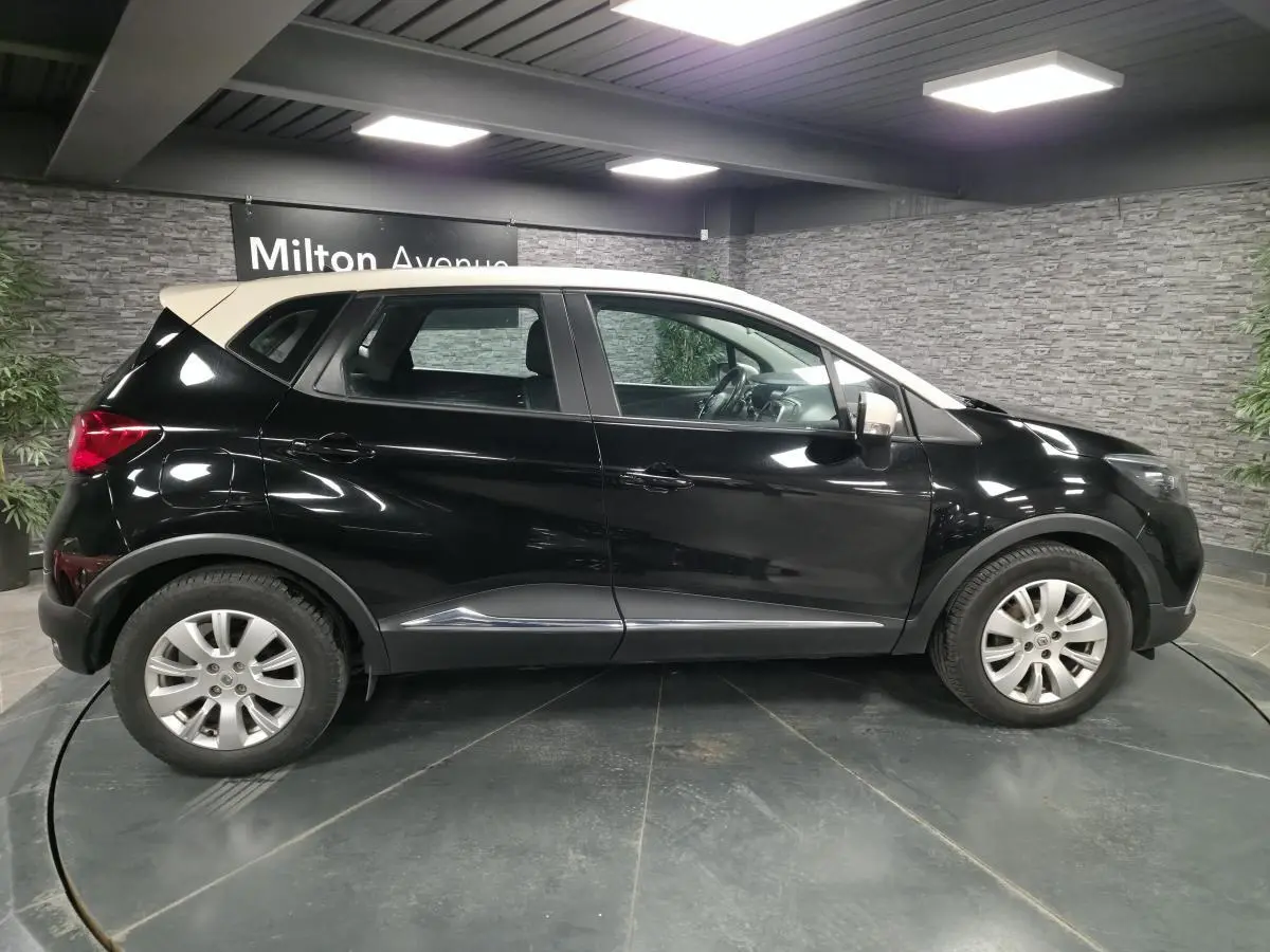 Renault Captur noir avec toit blanc en vue de profil côté gauche, dans un showroom intérieur.