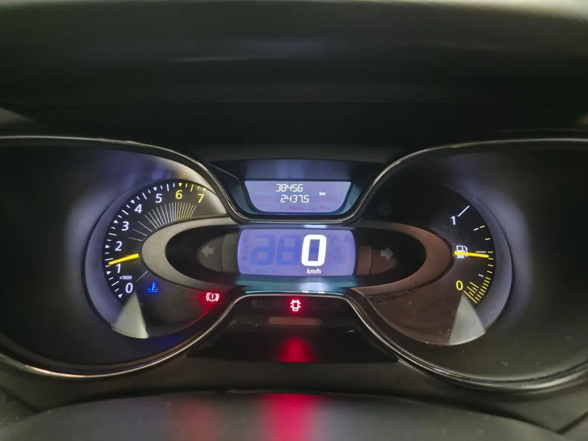 Tableau de bord numérique du Renault Captur noir 2014, affichant 0 km/h et compteurs éclairés en bleu et jaune.