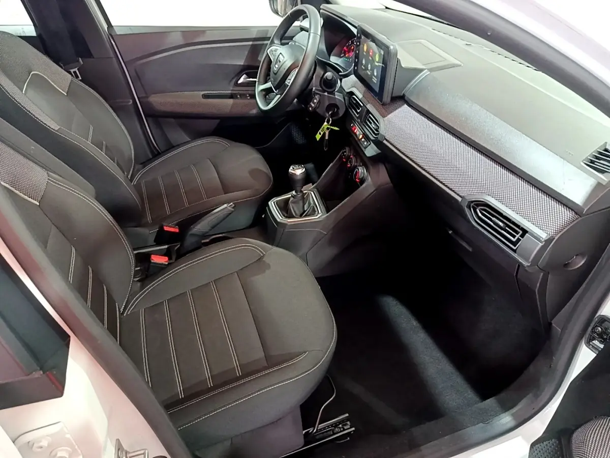 Vue intérieure côté passager de la Dacia Sandero Confort TCe 90 2022, sièges noirs et tableau de bord avec écran tactile.