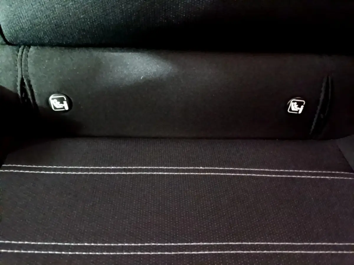 Gros plan sur la banquette arrière noire de la Dacia Sandero avec les logos de fixation Isofix visibles.