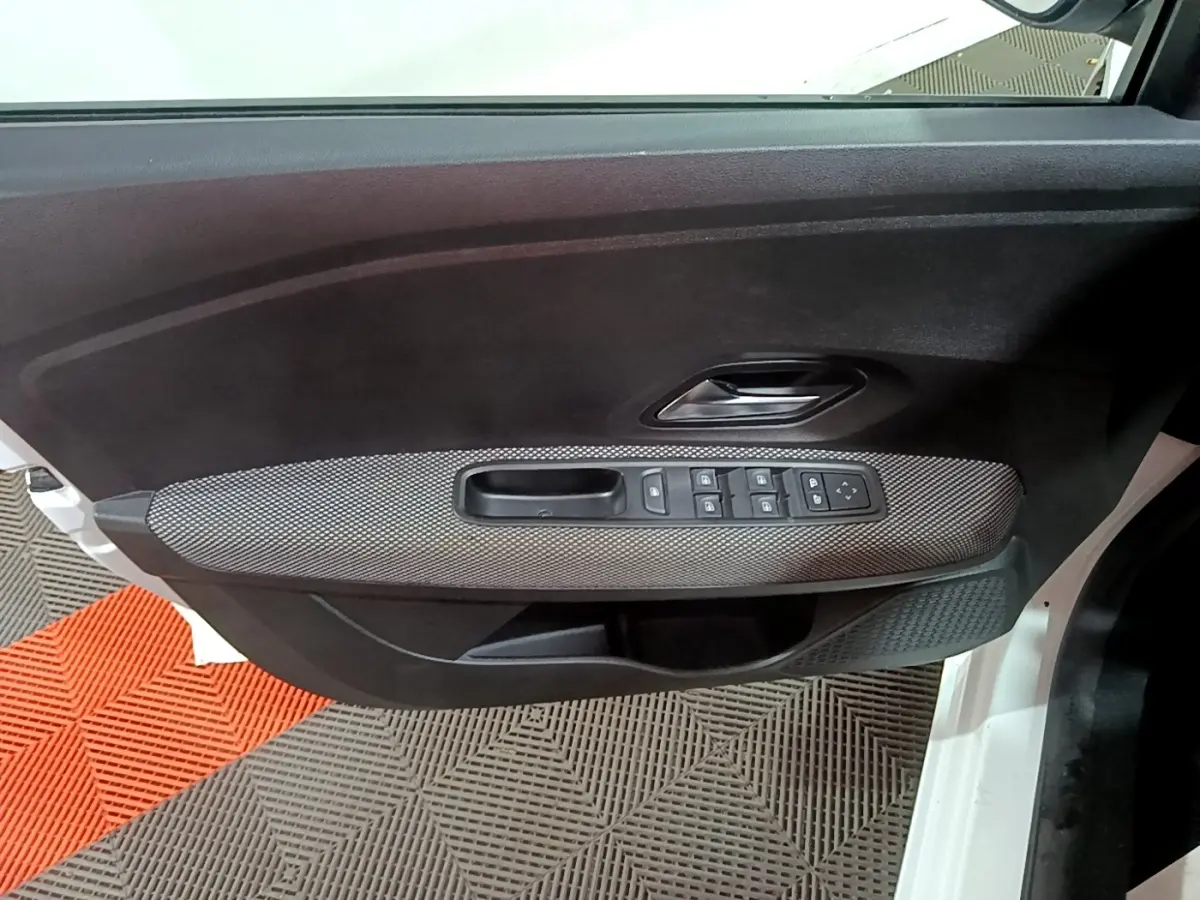 Vue intérieure côté gauche de la porte avant blanche de la Dacia Sandero avec commandes de vitres et poignée intégrée.