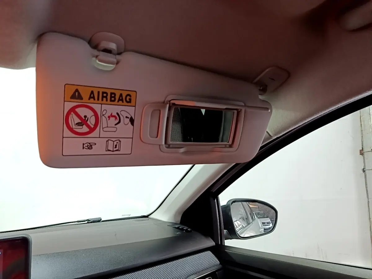 Intérieur de la Dacia Sandero blanc, vue côté passager avec pare-soleil ouvert et miroir de courtoisie visible.