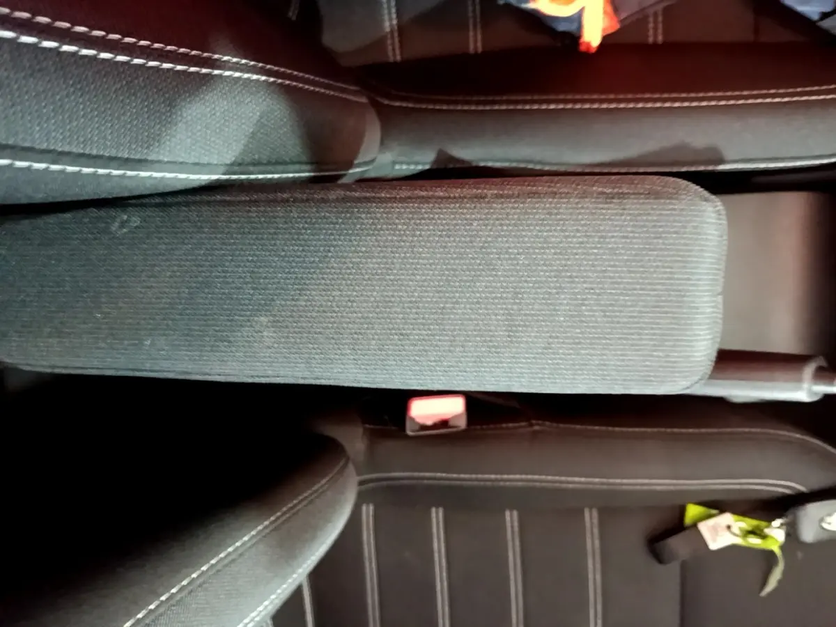 Vue rapprochée de l'accoudoir central et des sièges noirs à surpiqûres blanches de la Dacia Sandero Confort 2022.