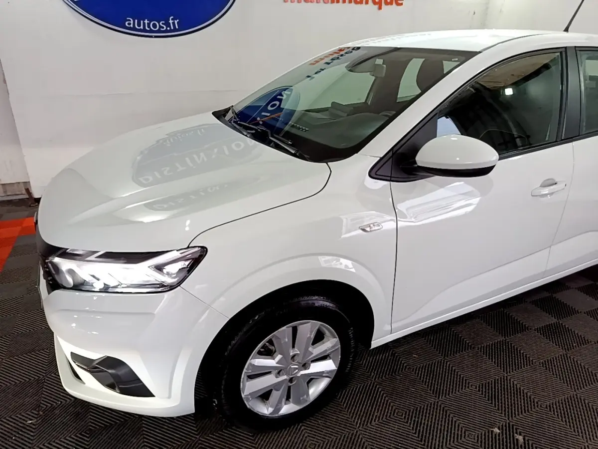 Vue 3/4 avant droite d'une Dacia Sandero blanche 2022 avec phares LED et jantes alliage visibles.