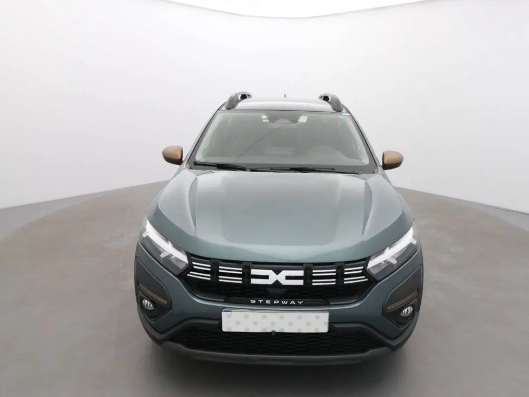 Vue frontale d'une Dacia Sandero Stepway 2025 vert cèdre avec détails bronze sur les rétroviseurs et calandre noire.