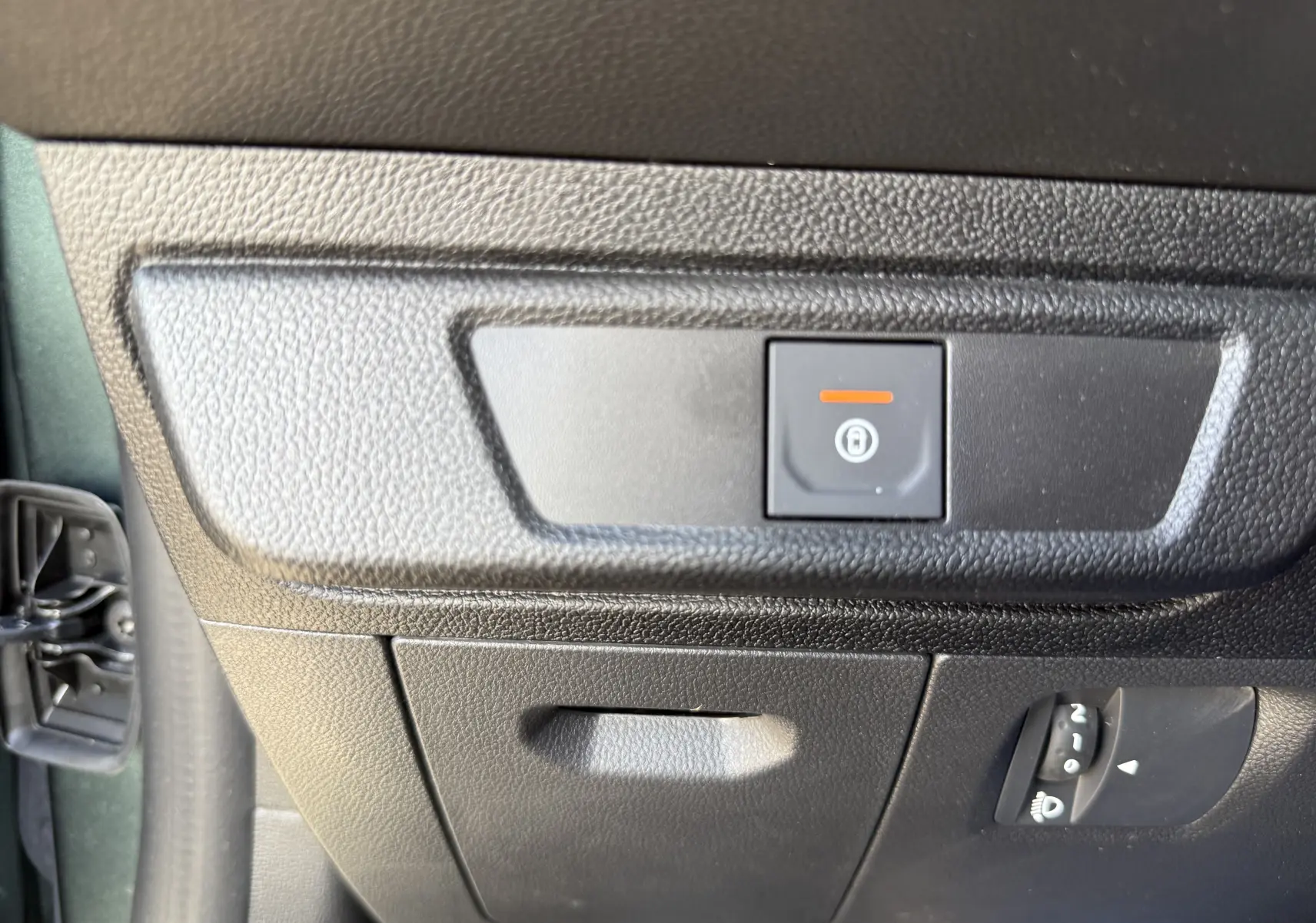 Gros plan sur le bouton de verrouillage centralisé sur la partie inférieure gauche du tableau de bord d’une Dacia Sandero Stepway Vert Cèdre.