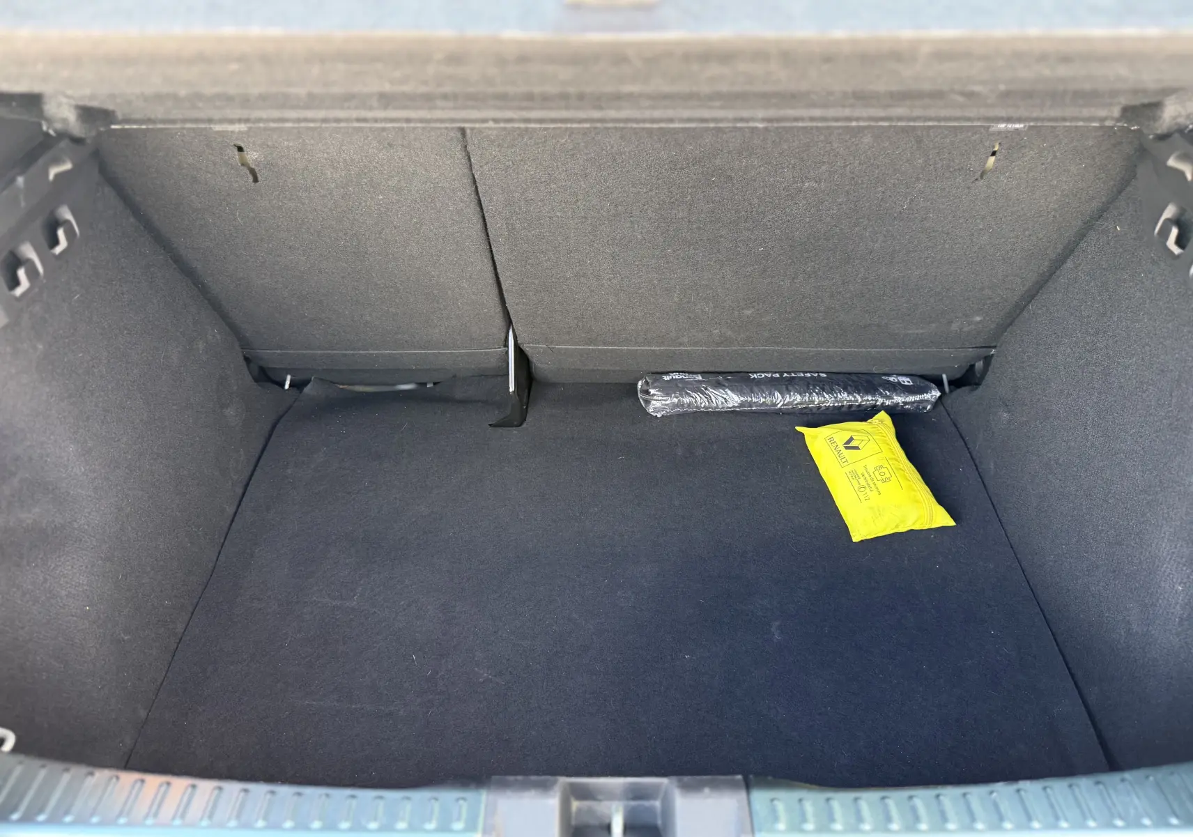 Coffre ouvert vu de l'arrière d'une Dacia Sandero Stepway vert cèdre, avec un kit de sécurité visible à l'intérieur.