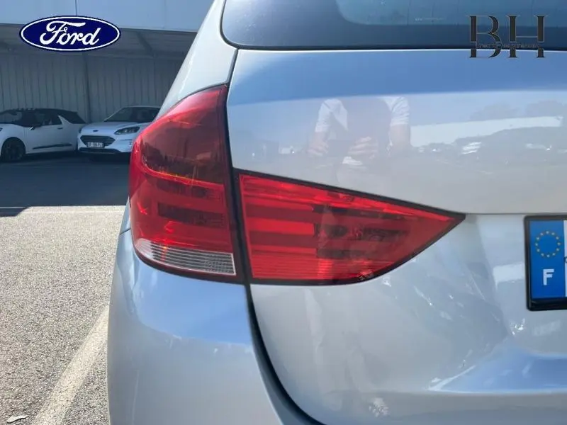 Feu arrière gauche d’une BMW X1 gris métal vue de près, avec plaque d’immatriculation française partielle visible.