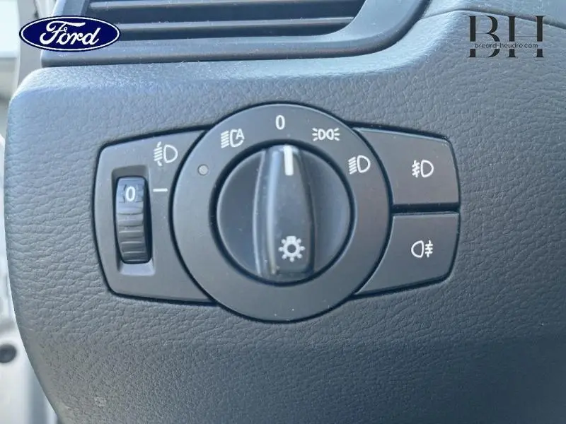 Gros plan sur le sélecteur d'éclairage intérieur d'une BMW X1 sDrive18dA gris, montrant les commandes des phares et feux antibrouillard.