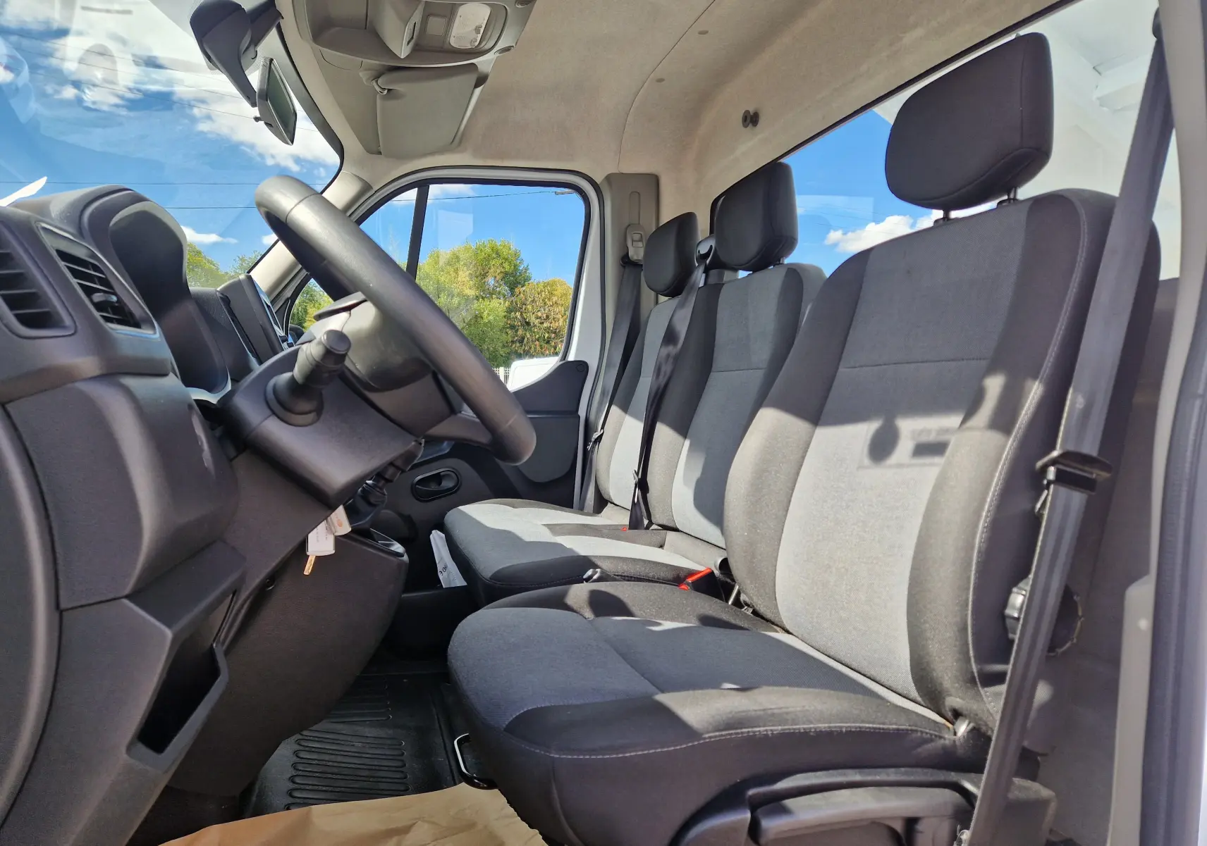Vue intérieure côté conducteur du Renault Master Châssis Cabine 2024, montrant les sièges gris et le volant noir.
