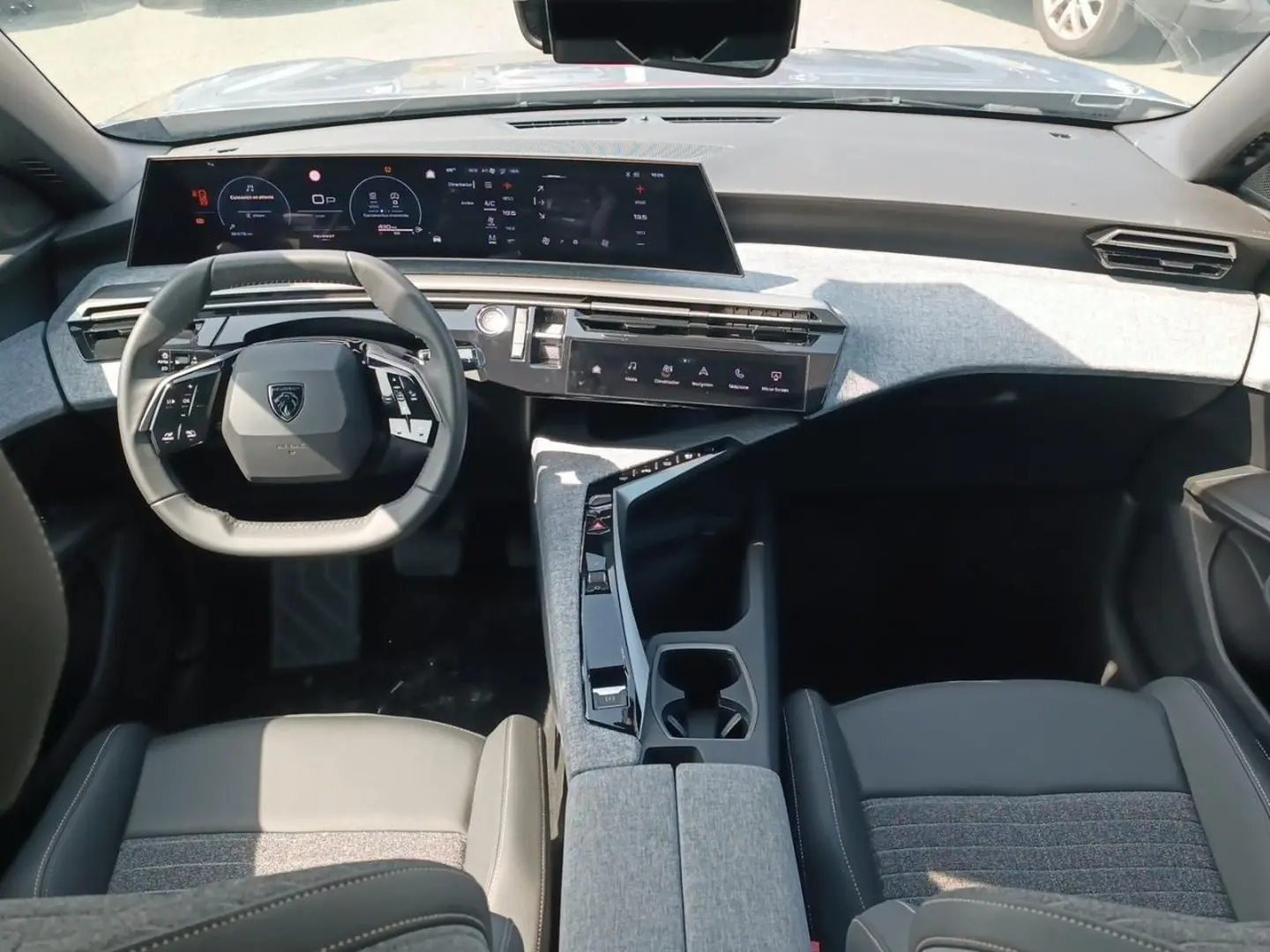 Vue intérieure avant du Peugeot 5008 Hybrid 145 allure e-dcs6 2025, tableau de bord moderne gris avec volant cuir multifonction.