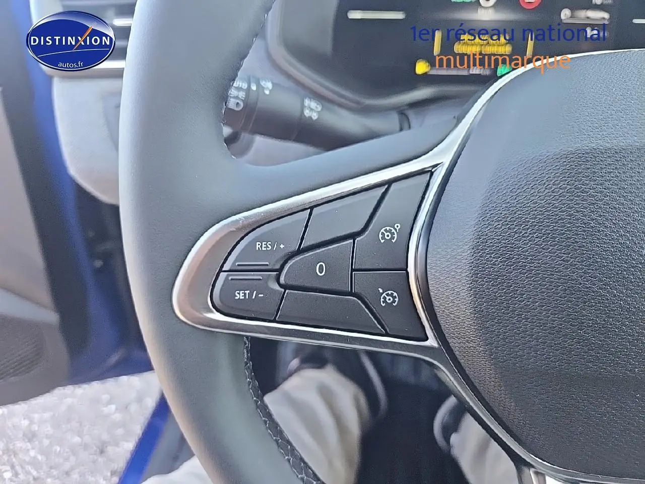 Gros plan sur les commandes au volant côté gauche d'une Renault Clio V bleu iron 2025 hybride essence.