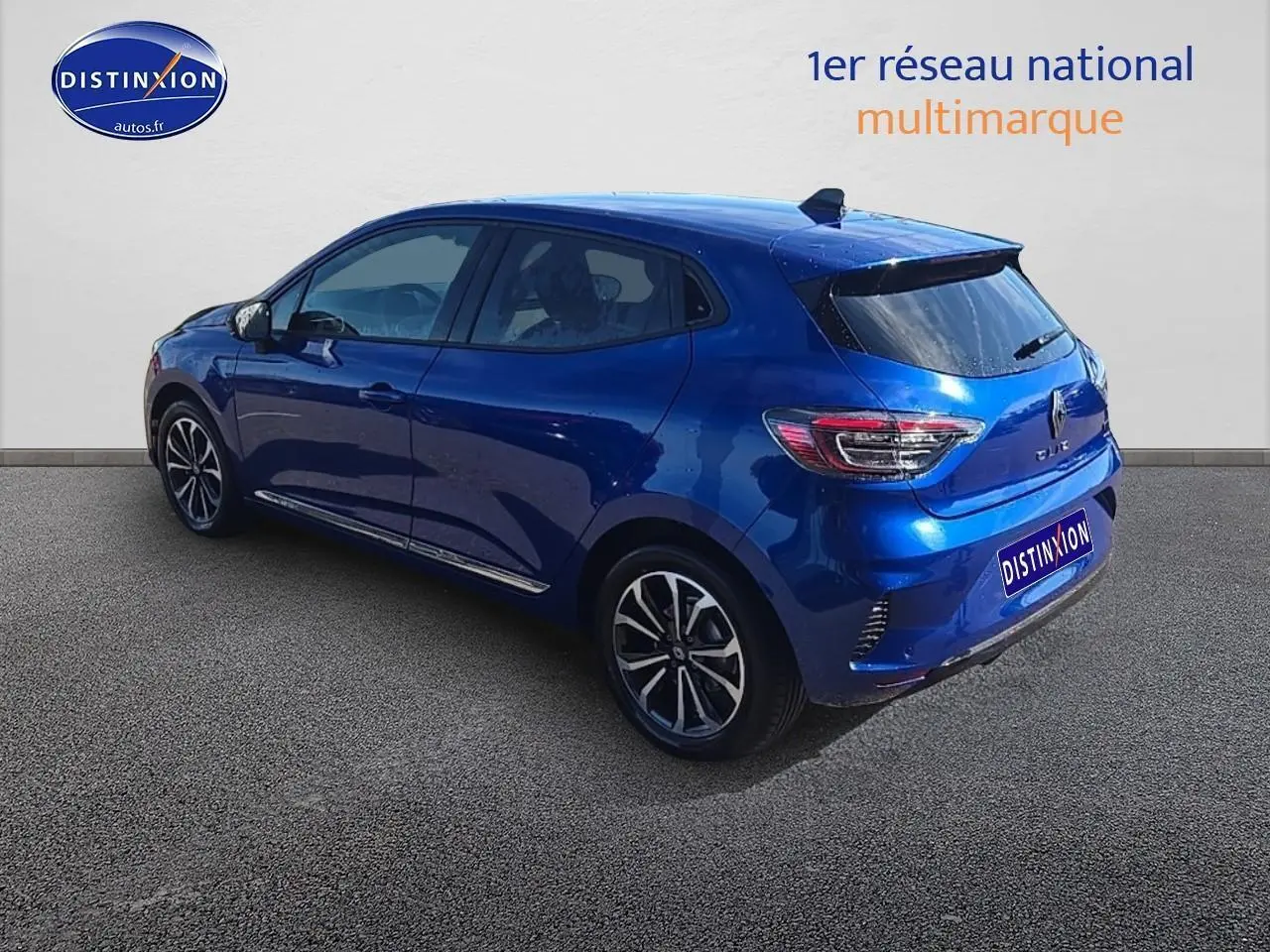 Renault Clio V bleu iron vue 3/4 arrière côté gauche, avec jantes alu et becquet arrière noir.