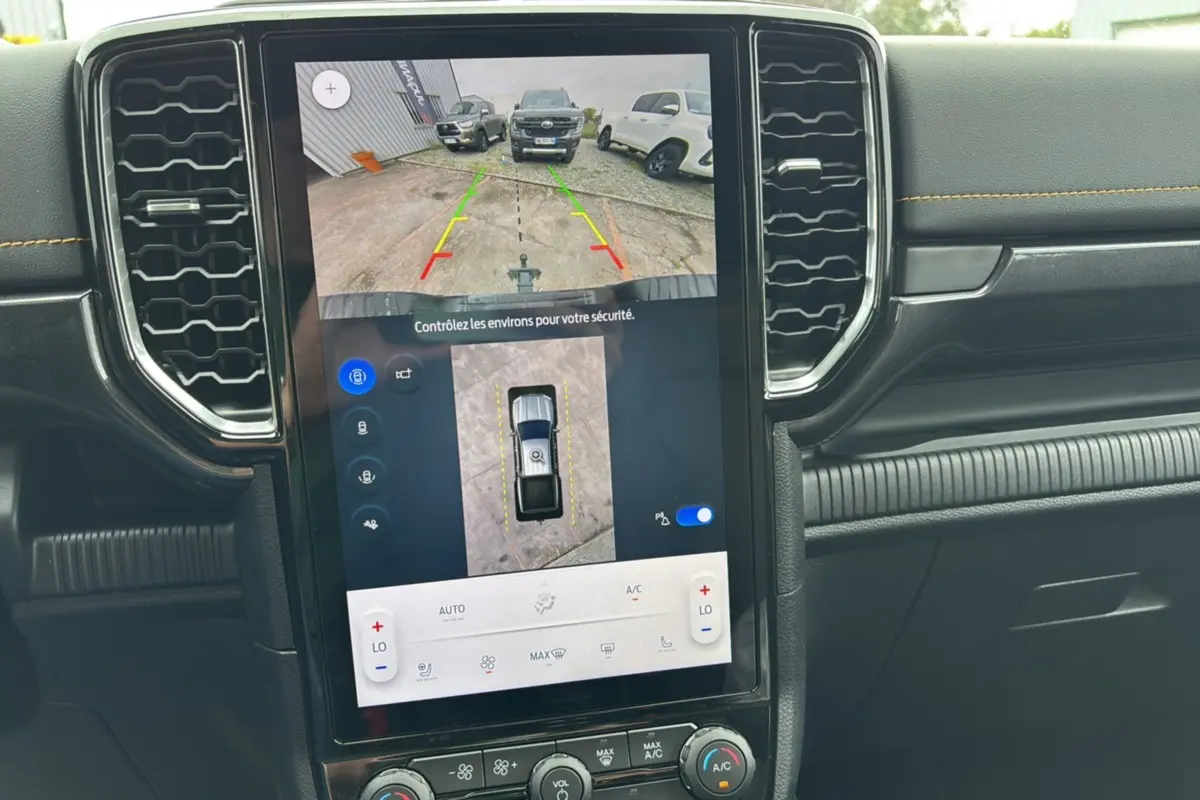 Écran central du Ford Ranger 2025 Wildtrak Plus montrant la caméra de recul avec vue aérienne, tableau de bord noir avec surpiqûres jaunes.
