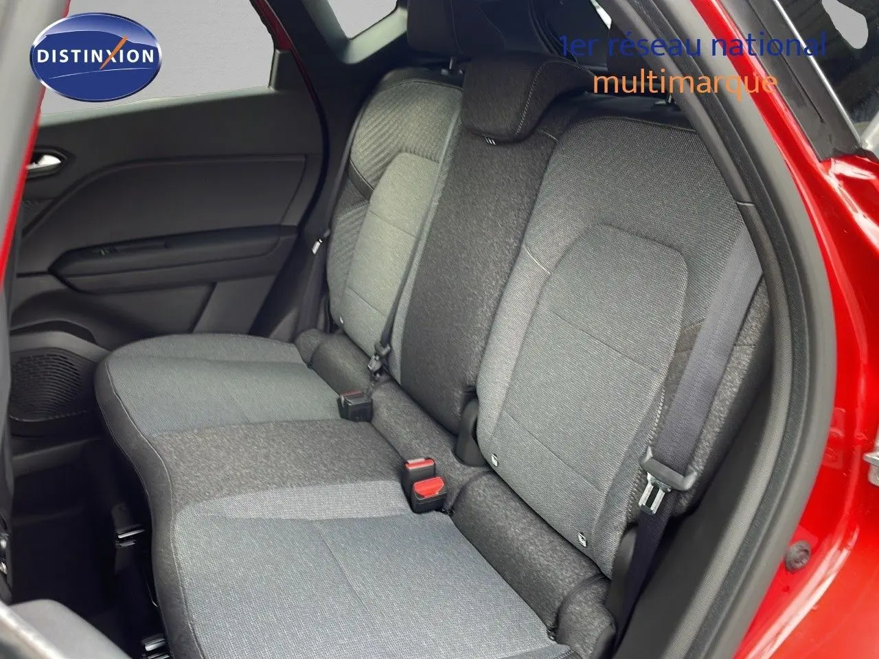 Vue intérieure sur les sièges arrière gris d'un Renault Captur rouge passion avec porte arrière ouverte côté droit.