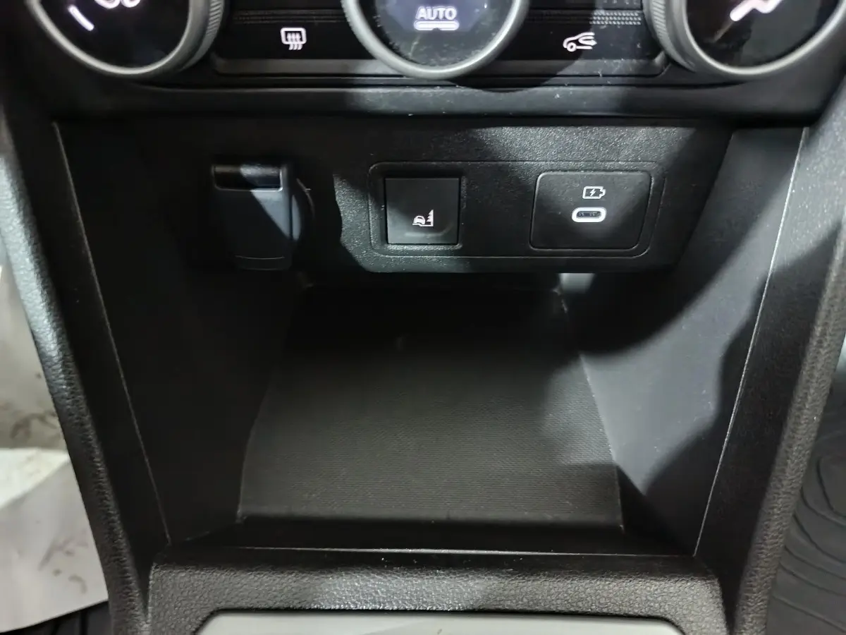 Gros plan sur la console centrale noire de la Dacia Sandero 2024 avec prise USB-C et bouton de siège chauffant.