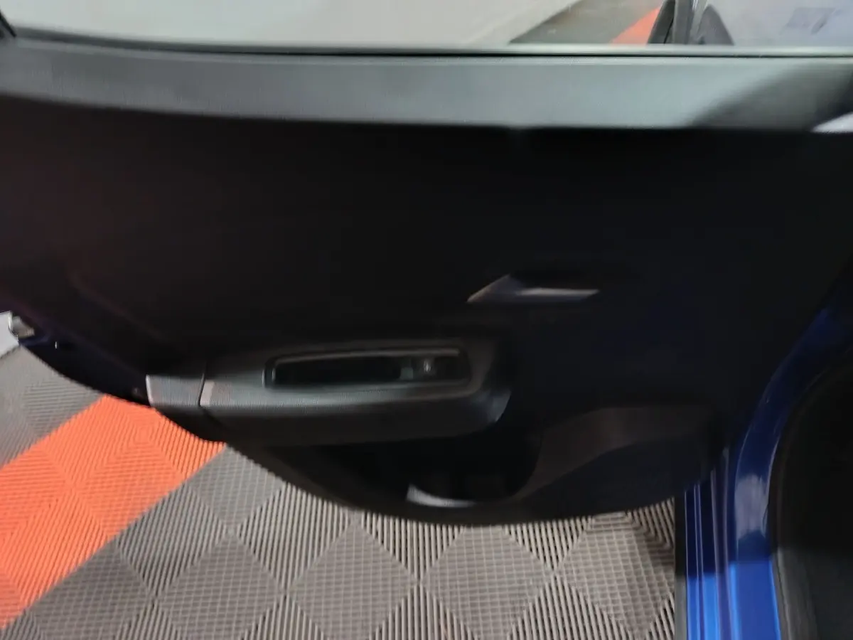 Vue rapprochée de la porte intérieure côté conducteur d'une Dacia Sandero Extreme+ bleu 2024, avec poignée et commande de vitre.