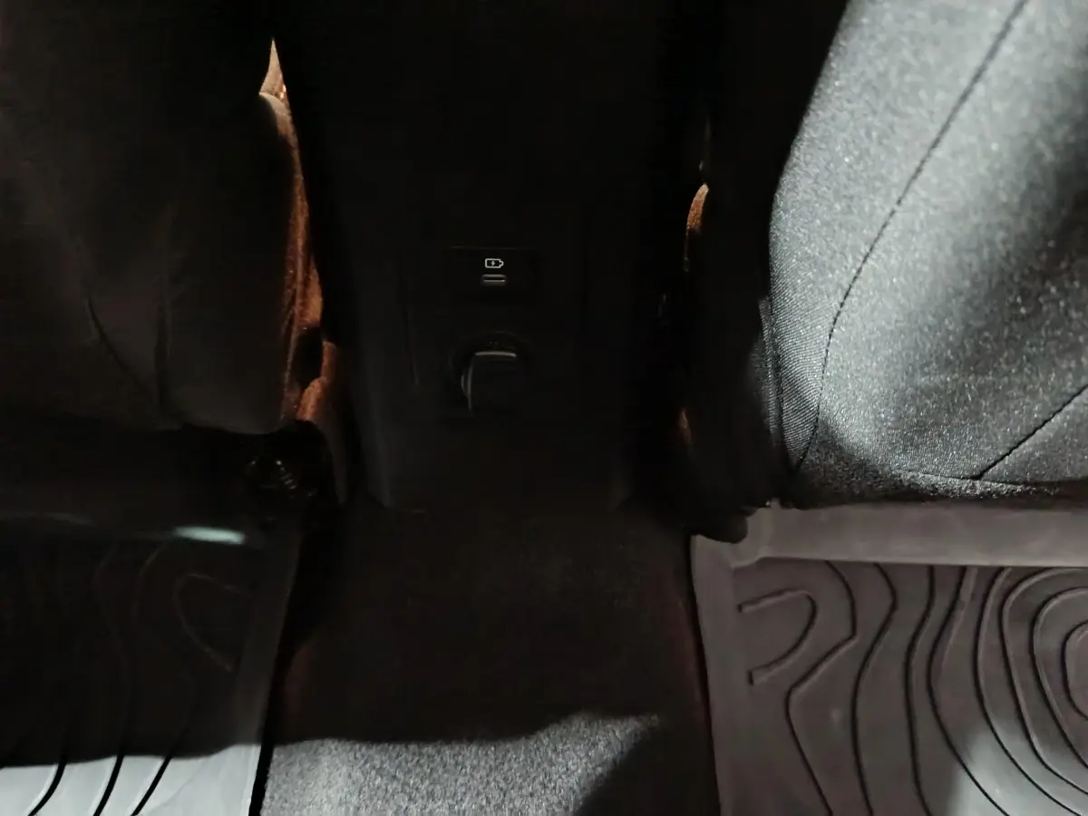 Vue rapprochée de la prise 12V et port USB entre les sièges arrière noirs du Dacia Sandero Extreme+ bleu.