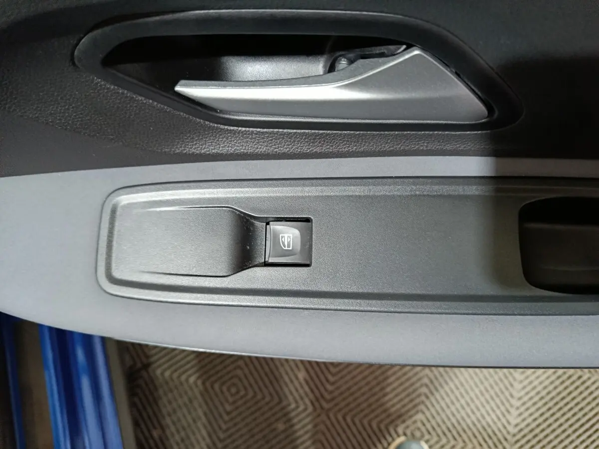 Gros plan sur la commande de lève-vitre côté conducteur de la Dacia Sandero Extreme+ TCe 110 bleu 2024.