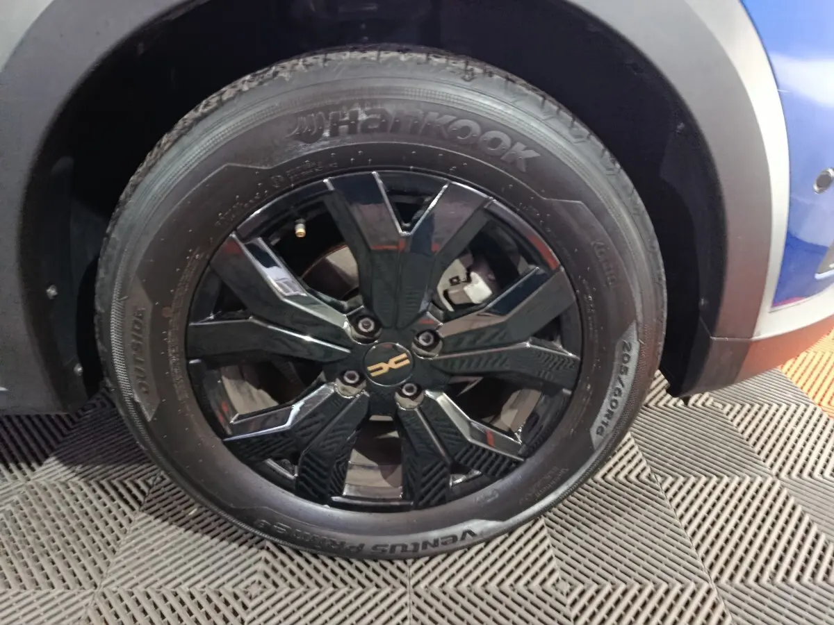 Gros plan sur la roue avant droite noire brillante d'une Dacia Sandero Extreme+ bleu 2024.