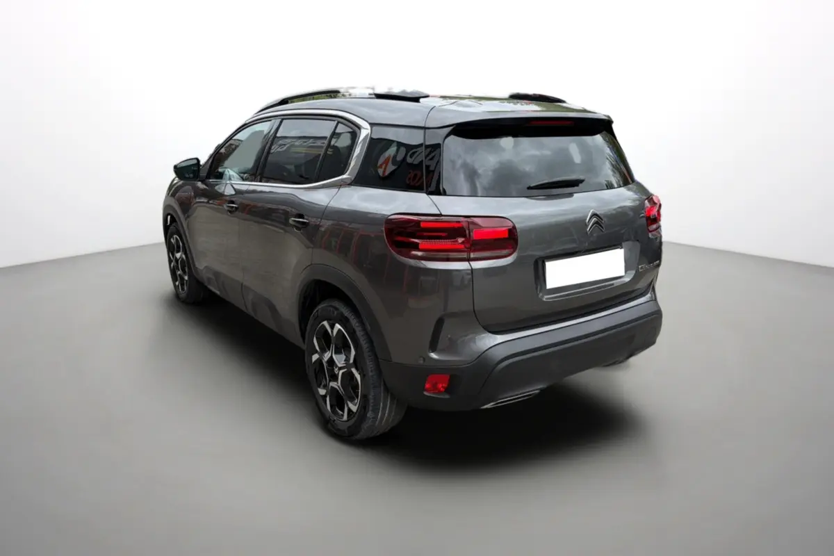 Vue 3/4 arrière gauche d'un Citroën C5 Aircross Hybrid 145 gris platinium avec barres de toit et vitres surteintées.