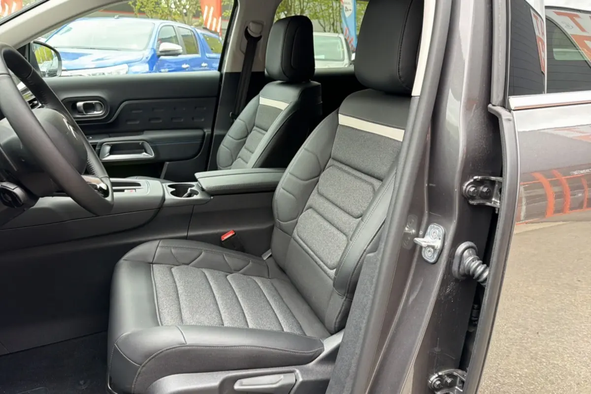 Vue intérieure côté conducteur du Citroën C5 Aircross gris platinium, mettant en valeur le siège avant en cuir et tissu avec accoudoir central.
