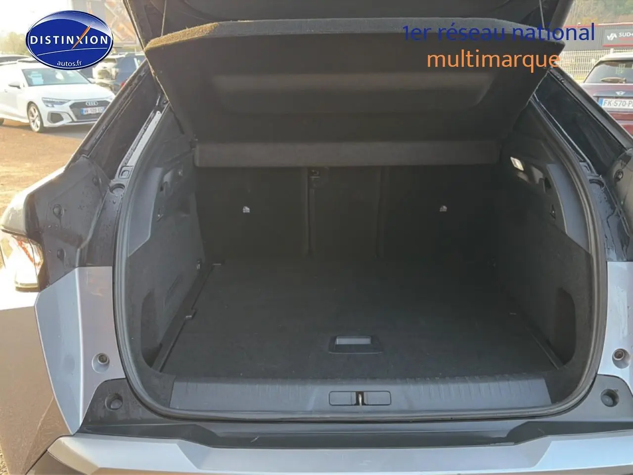 Coffre ouvert d’un Peugeot 3008 gris vu de l’arrière, montrant l’espace de chargement vide et la trappe de plancher.