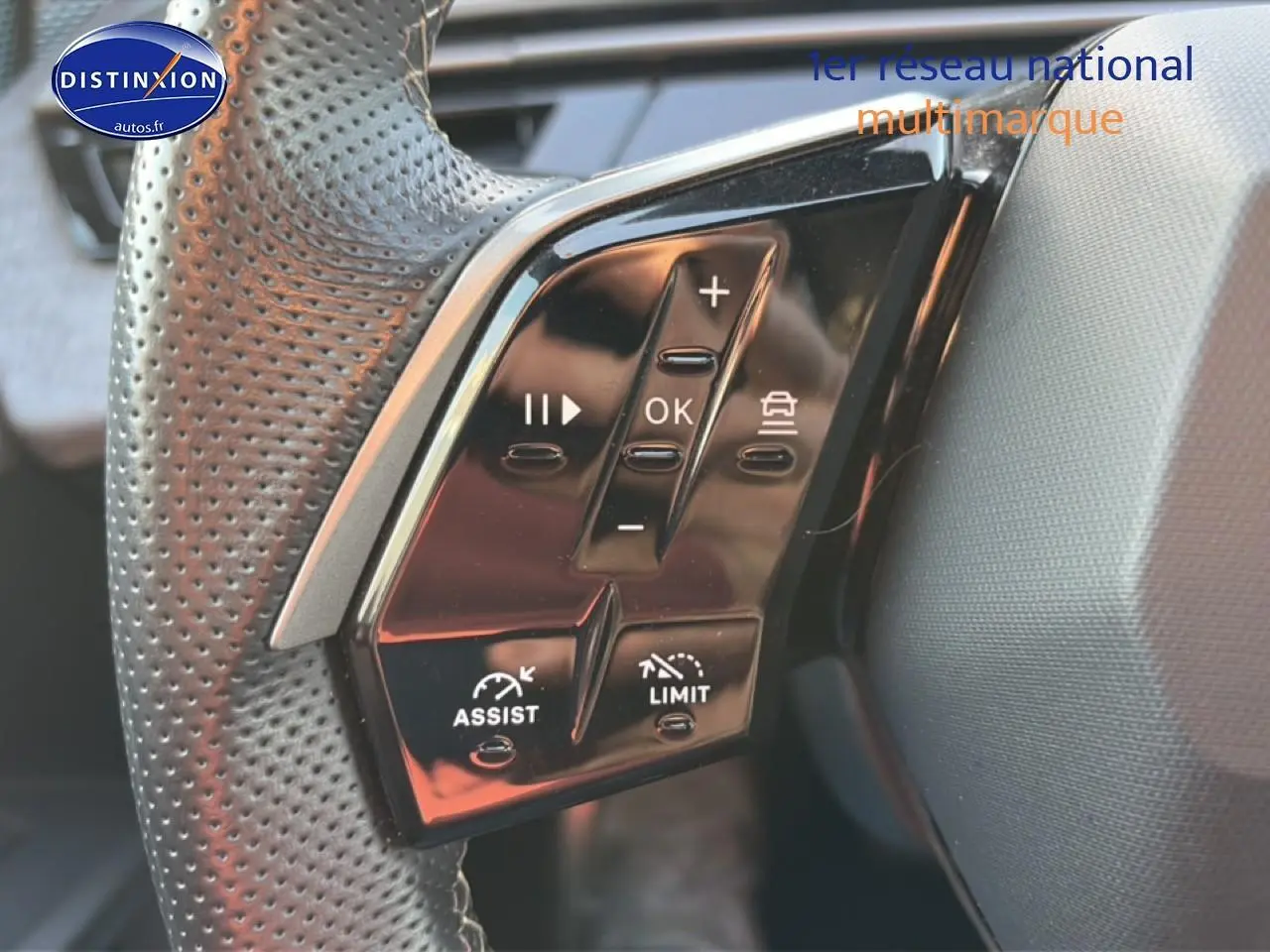 Gros plan sur les commandes multifonctions noires du volant cuir perforé côté gauche du Peugeot 3008 gris 2025.