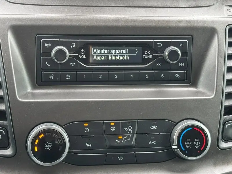 Tableau de bord du Ford Transit Fourgon blanc, affichant l'autoradio avec menu Bluetooth et commandes de climatisation.
