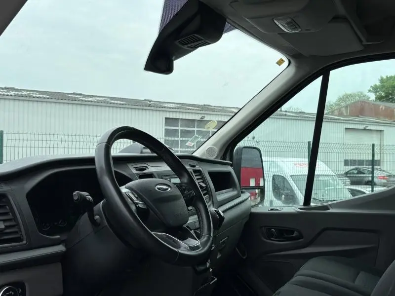 Intérieur du Ford Transit Fourgon blanc, vue côté conducteur sur le volant cuir multifonction et tableau de bord moderne.