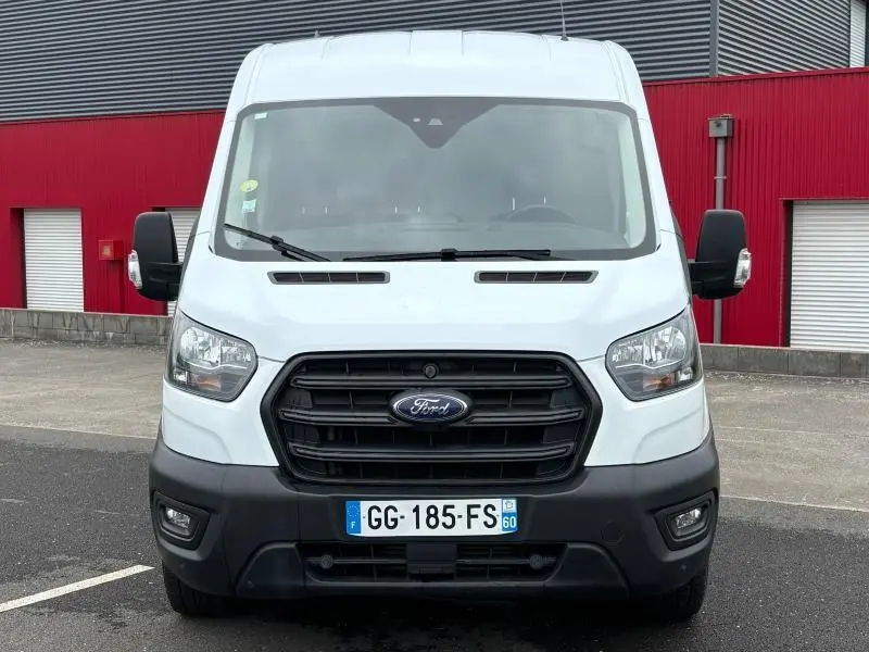 Vue frontale d'un Ford Transit Fourgon blanc glacier avec calandre noire et plaques d'immatriculation françaises.