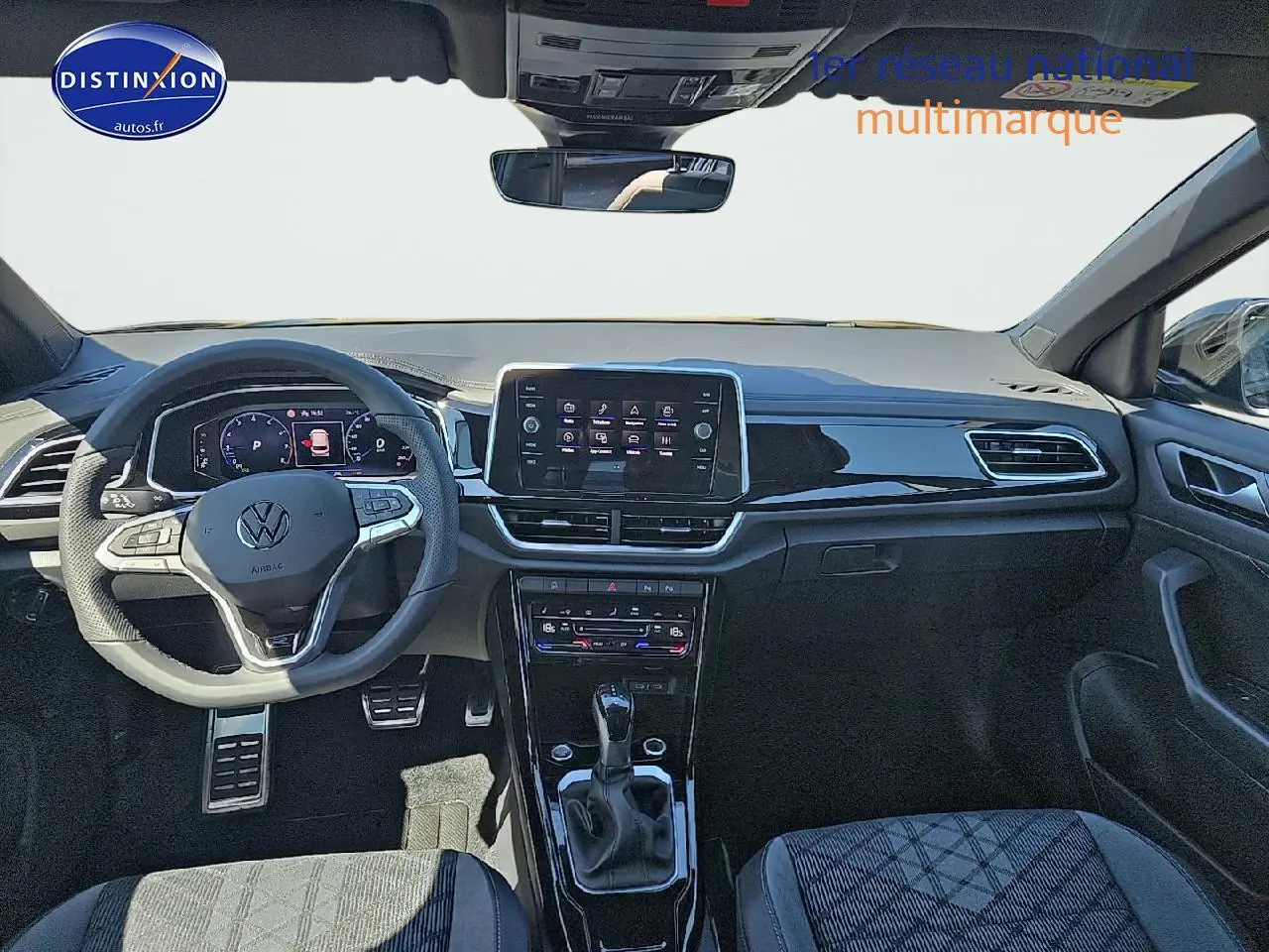 Intérieur avant du Volkswagen T-Roc noir perle 2025 avec tableau de bord numérique et volant multifonction sport.