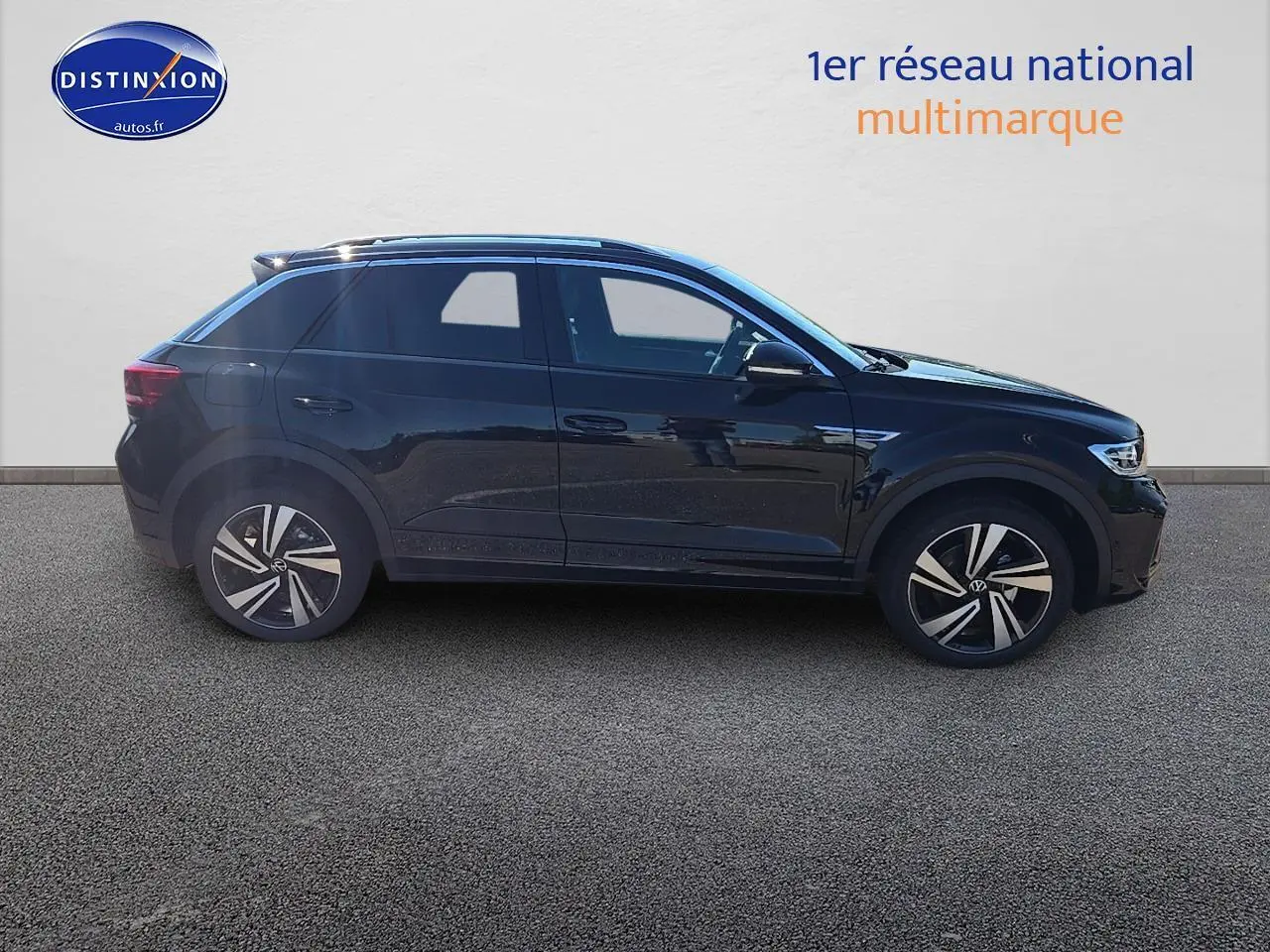 Profil côté gauche d'un Volkswagen T-Roc noir perle 2025 finition R-Line avec jantes alliage et barres de toit argentées.
