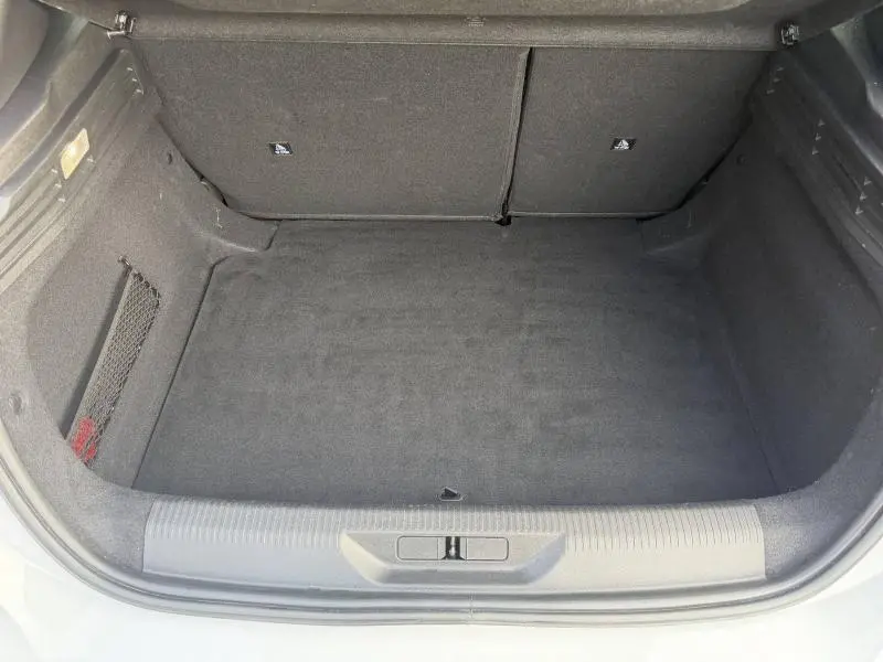 Coffre ouvert vu de dessus d'une Peugeot 308 2024 blanc Okénite, montrant un espace de chargement vide et propre.