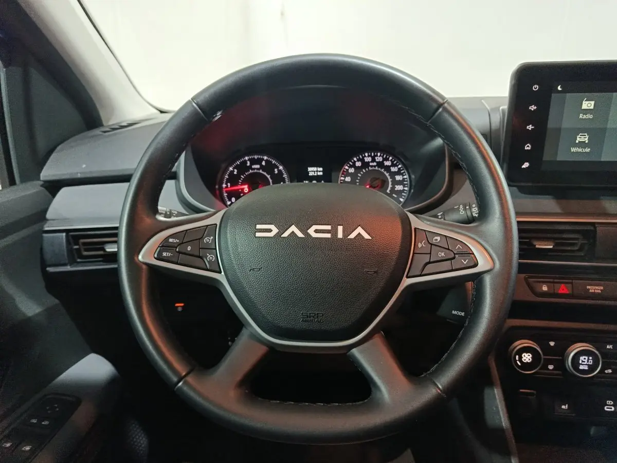 Vue rapprochée du volant cuir noir multifonctions de la Dacia Sandero 2024 avec tableau de bord et écran tactile.