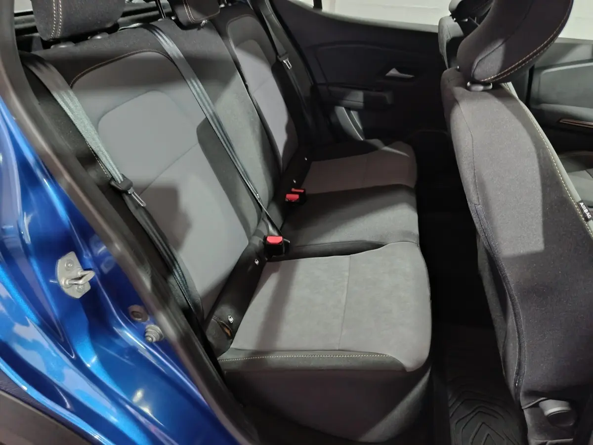 Vue intérieure côté gauche des sièges arrière gris foncé d'une Dacia Sandero Extreme+ TCe 110 bleu 2024 avec portière ouverte.