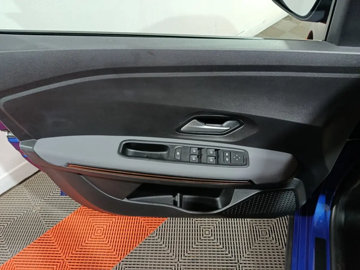 Vue rapprochée de la porte avant gauche bleu de la Dacia Sandero Extreme+ avec commandes électriques et poignée intégrée.