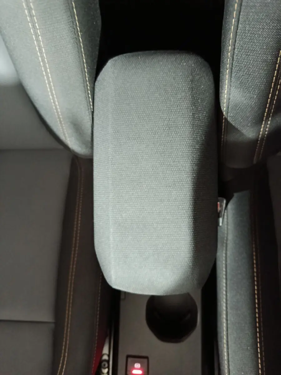 Vue plongeante sur l'accoudoir central tissu gris entre les sièges avant du Dacia Sandero Extreme+ 2024.
