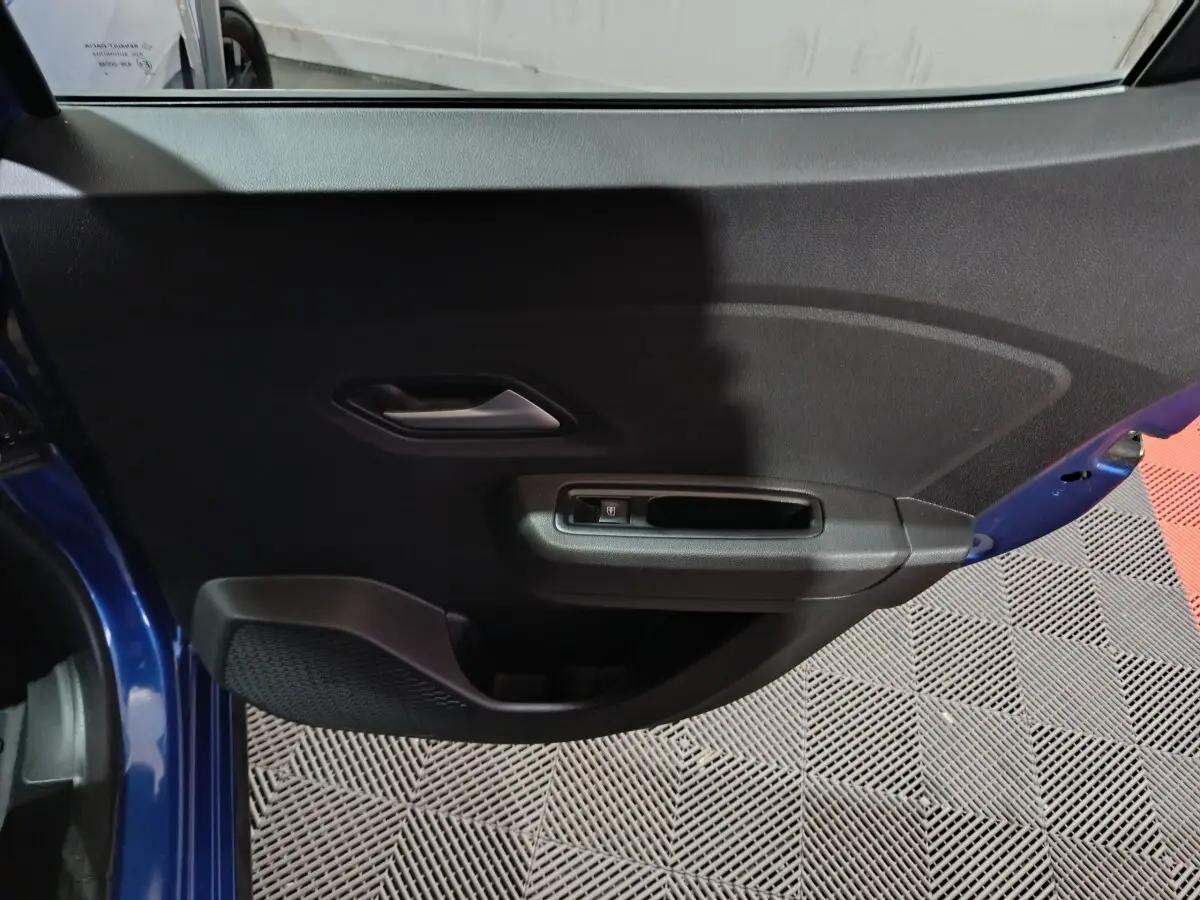 Vue rapprochée de la porte avant gauche bleue de la Dacia Sandero Extreme+ avec poignée intérieure et commande de vitre électrique.