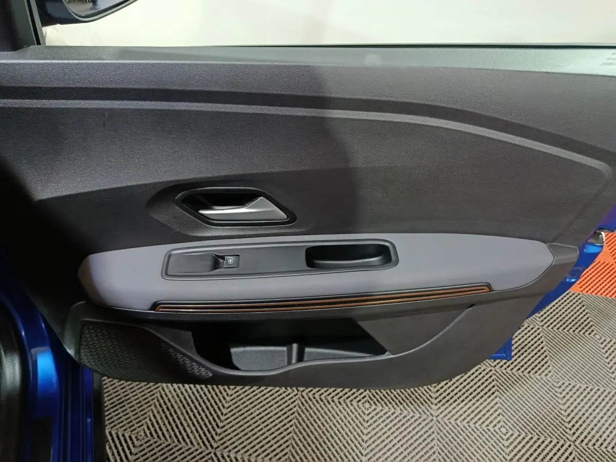 Vue rapprochée de la porte avant gauche bleu métallisé de la Dacia Sandero Extreme+ TCe 110 avec commande de vitre électrique.