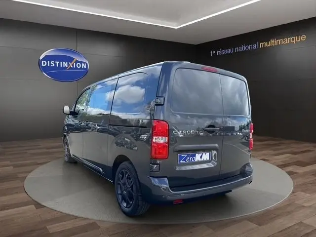 Vue 3/4 arrière droite d’un Citroën Jumpy gris foncé avec portes arrière pleines dans un showroom.