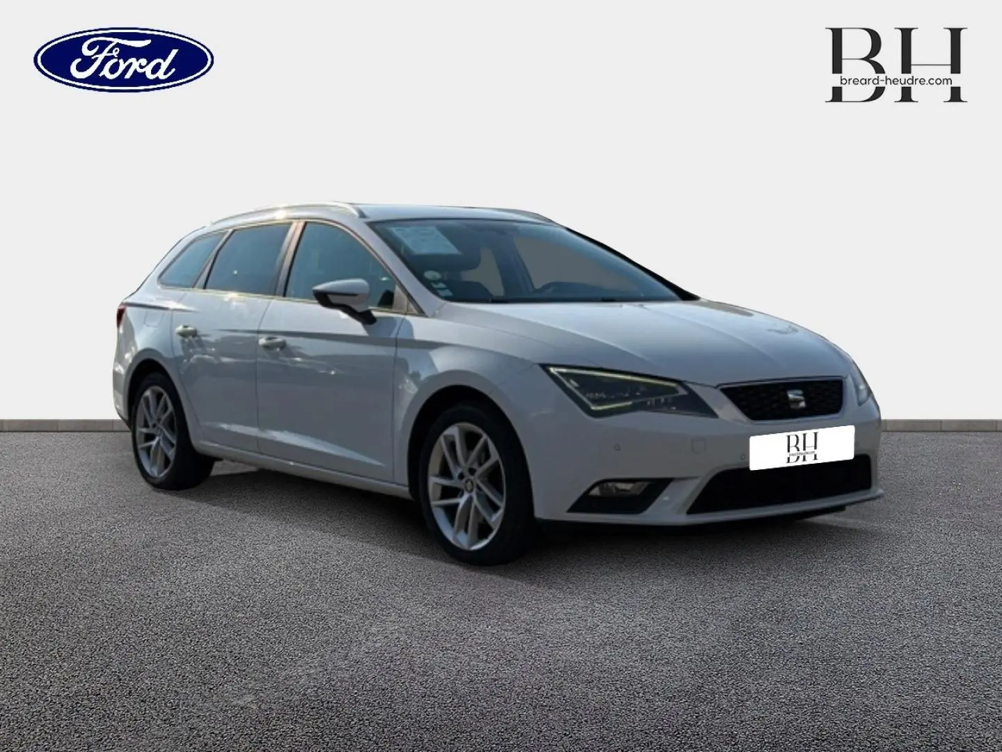 SEAT Leon ST gris étoile vue 3/4 avant droit, break compact avec jantes alliage et barres de toit visibles.