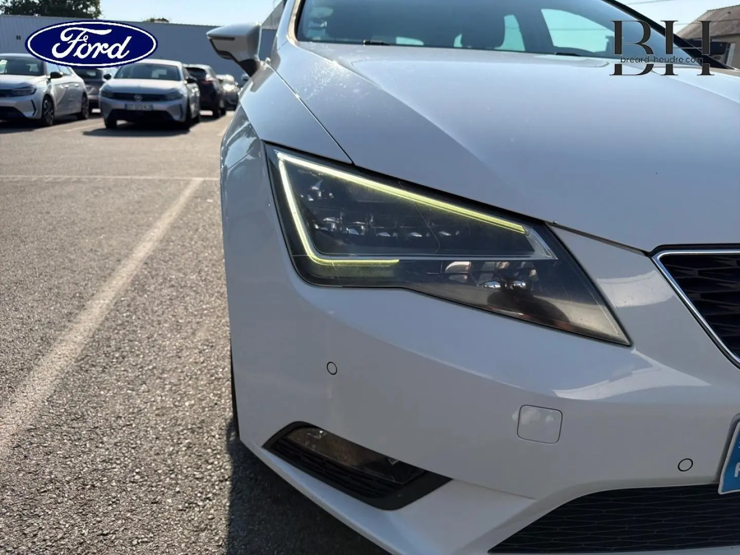 Gros plan sur l'avant droit gris étoile d'une SEAT Leon ST 2017, mettant en valeur le phare LED et la calandre.