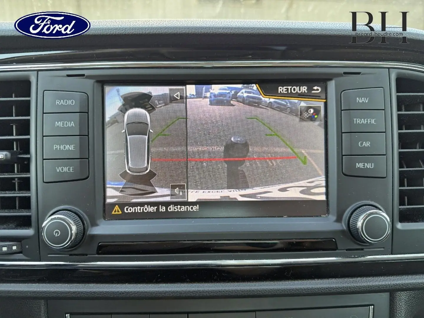 Écran tactile de système multimédia Ford montrant la caméra de recul avec alertes de distance, tableau de bord noir.