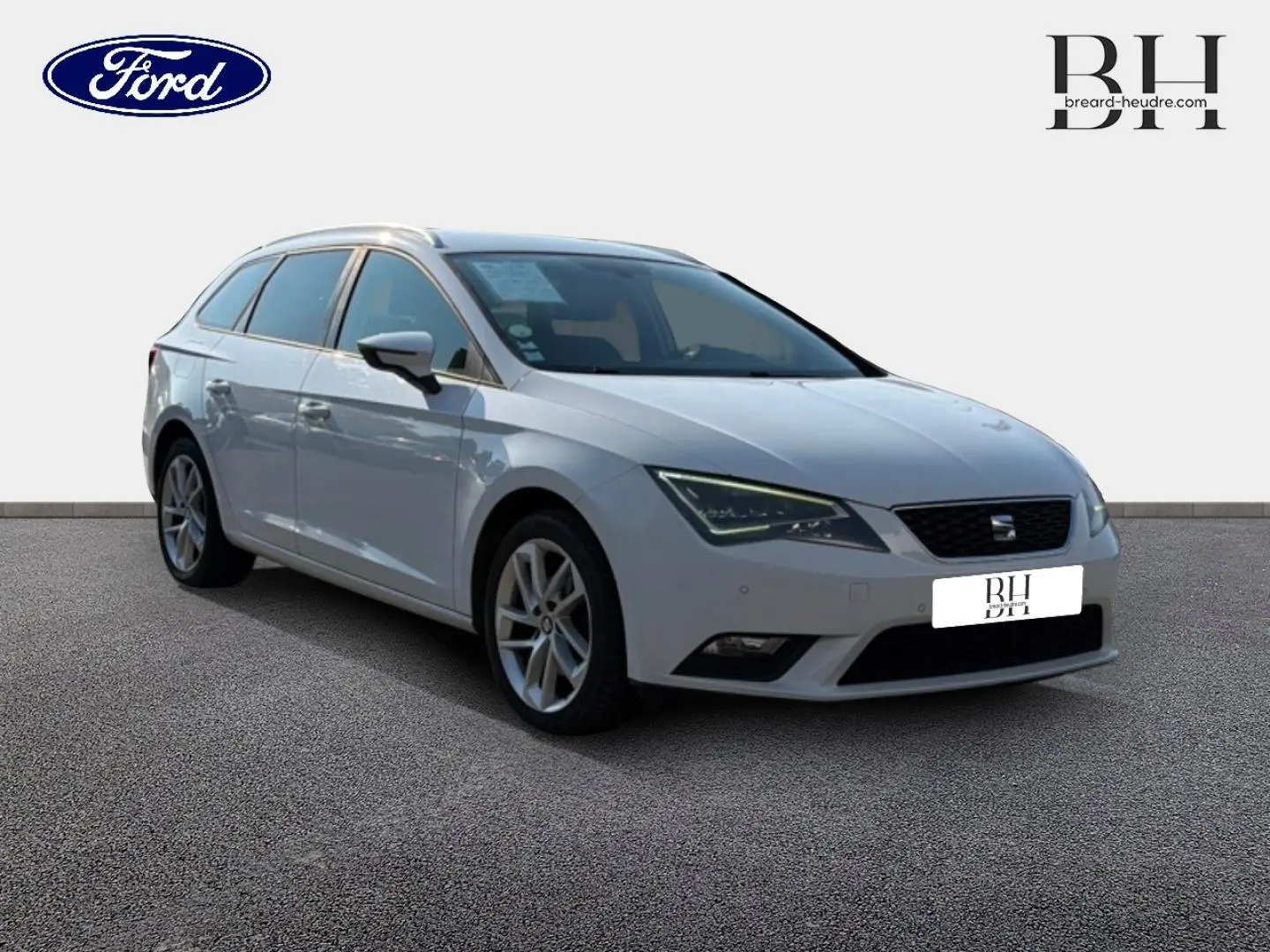 SEAT Leon ST gris étoile vue 3/4 avant droit, break compact avec jantes alliage et barres de toit visibles.
