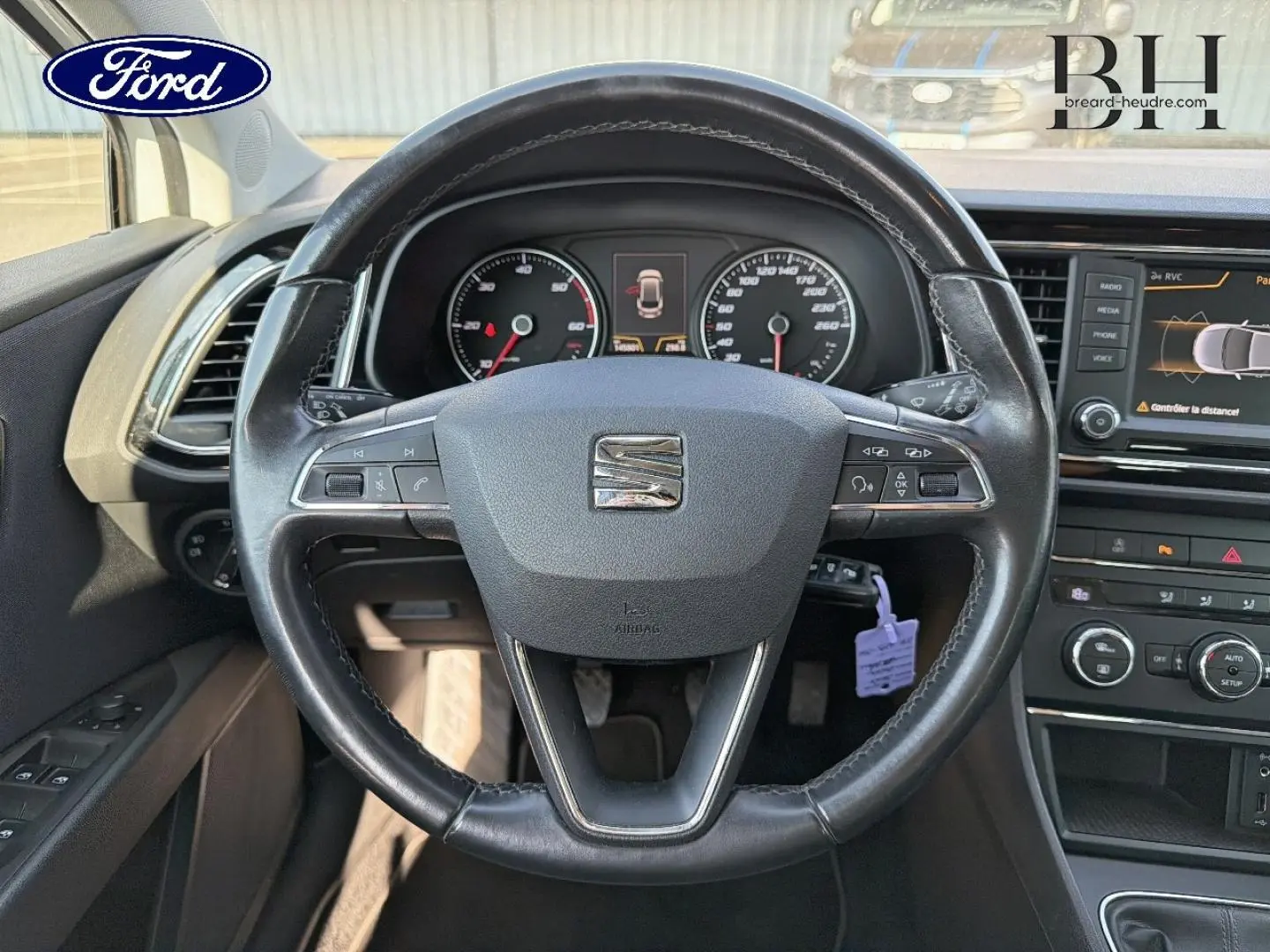 Vue intérieure centrée sur le volant cuir noir de la SEAT LEON ST avec tableau de bord et écran tactile visibles.