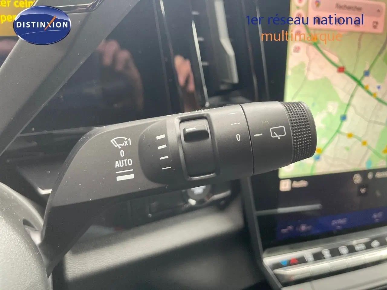 Gros plan sur la commande d'essuie-glace du Renault Austral gris schiste, avec écran tactile et navigation visible en arrière-plan.