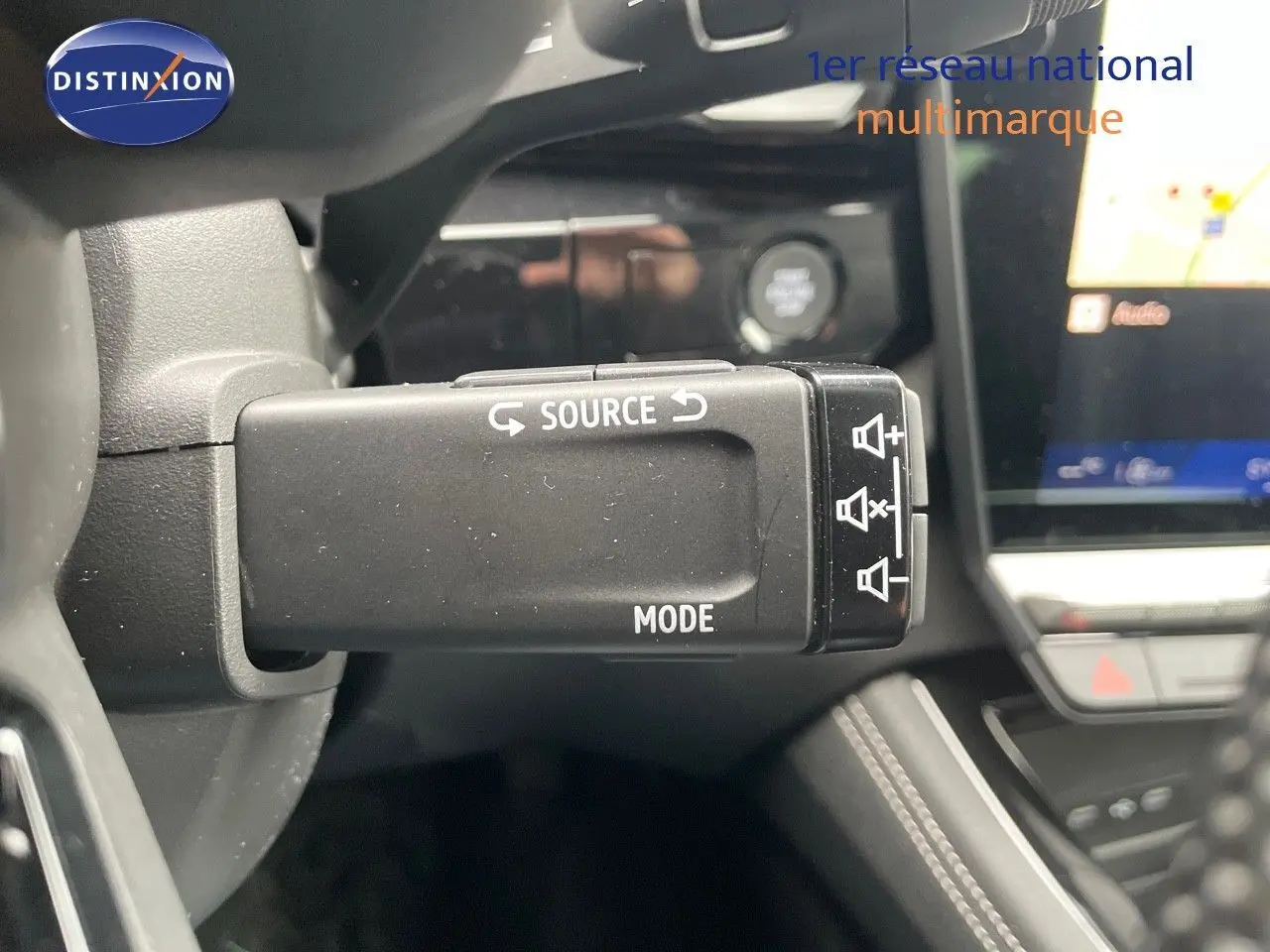 Gros plan sur la commande au volant du mode audio du Renault Austral E-Tech gris schiste, avec tableau de bord en arrière-plan.