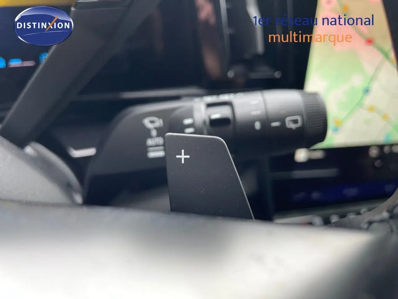 Gros plan sur la palette de changement de vitesse "+" du volant d'un Renault Austral gris schiste hybride 2025.
