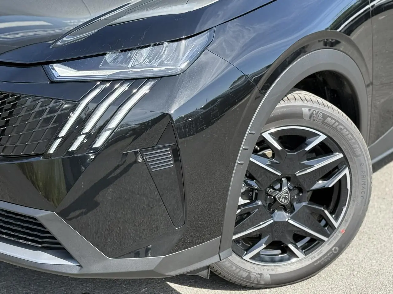 Gros plan sur l'avant droit noir Perla du Peugeot 3008 Hybrid 145 Allure, mettant en valeur les feux LED et la jante alliage 19''.